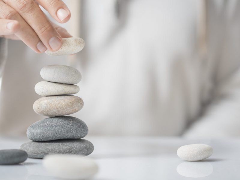 Horizontal image of a man stacking pebbles on a table with copyspace for text. Concept of personal development or self realization.